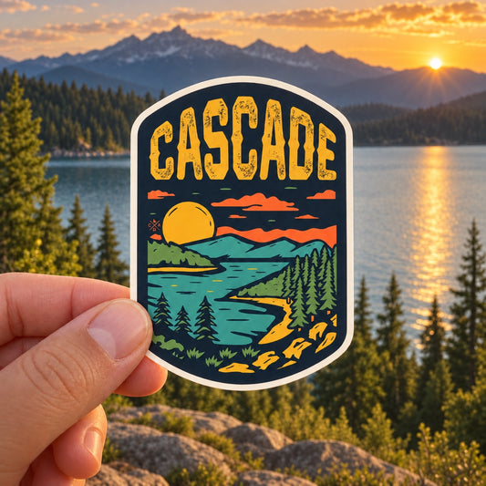 Cascade Idaho Golden Hour sticker held outdoors above a mountain lake