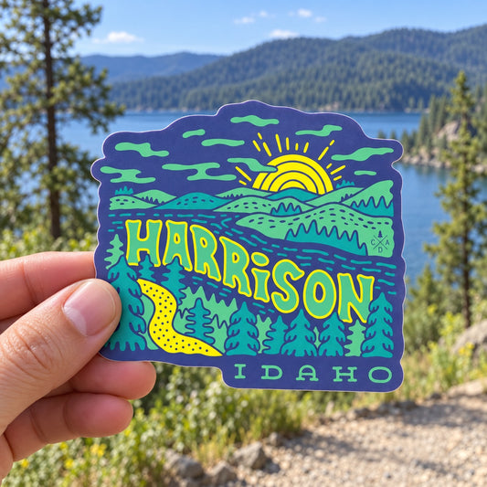 Groovy Harrison Idaho sticker held outdoors above a North Idaho lake